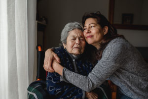 An adult woman hugging a senior woman