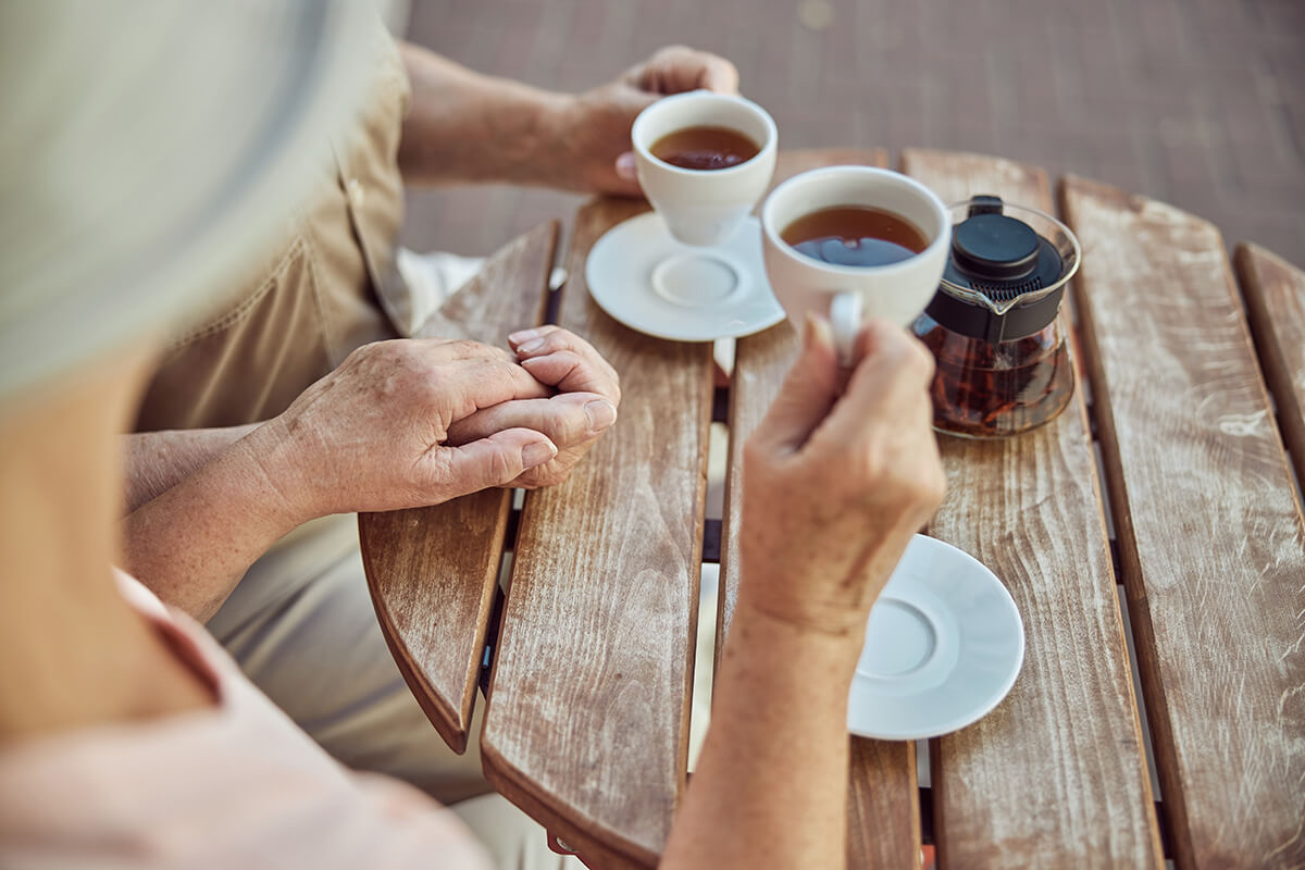 Senior couple drinking tea at a wooden table outdoors