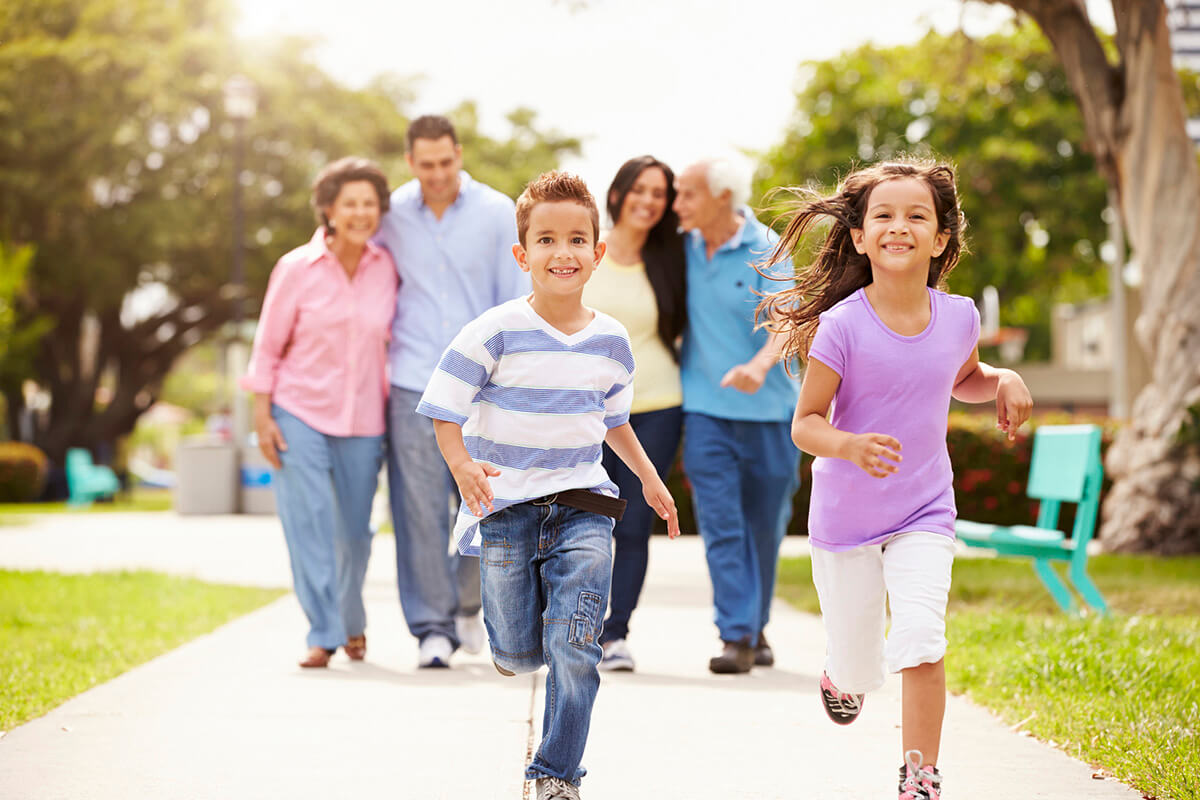 Two kids happily running in front of their parents and grandparents.